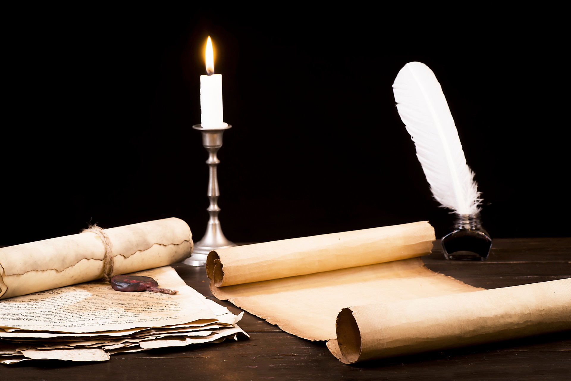 Scrolls of parchment and old papers on the background of a lit candle and inkwell pen